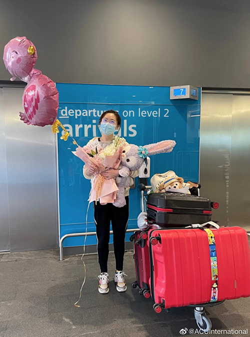  Female student with suitcases at airport holding balloons and soft toy