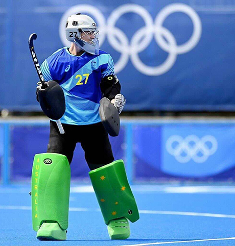  Female hockey player wearing green shin pads and blue team shirt