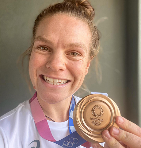  Olympian Rowena Meredith smiling and holding up her bronze medal from Tokyo 2020