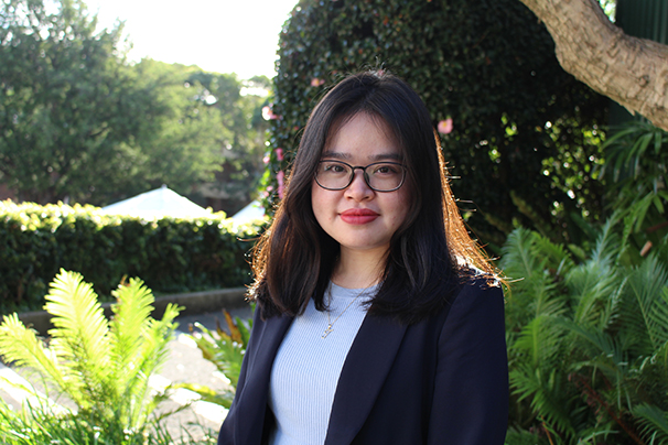  a young woman with dark hair wearing glasses, a dark blazer and a pale ribbed top