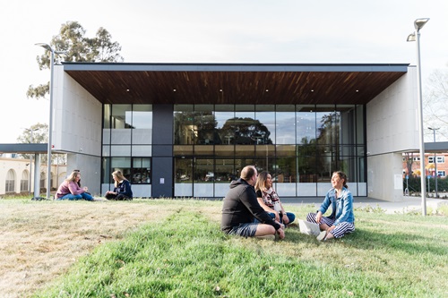 students sitting on the green law in front of ACU Canberra campus